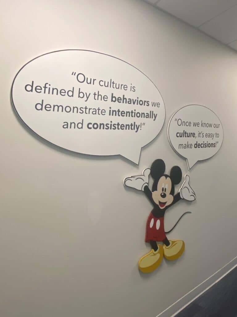 Poster of Mikey Mouse stating "Our culture is defined by the behaviors we demonstrate intentionally and consistently!" and "Once we know the culture, it's easy to make decisions!"