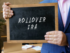 Investor holding a chalkboard that says "Rollover IRA", displaying that we will learn about rolling over a 401(k) to an IRA