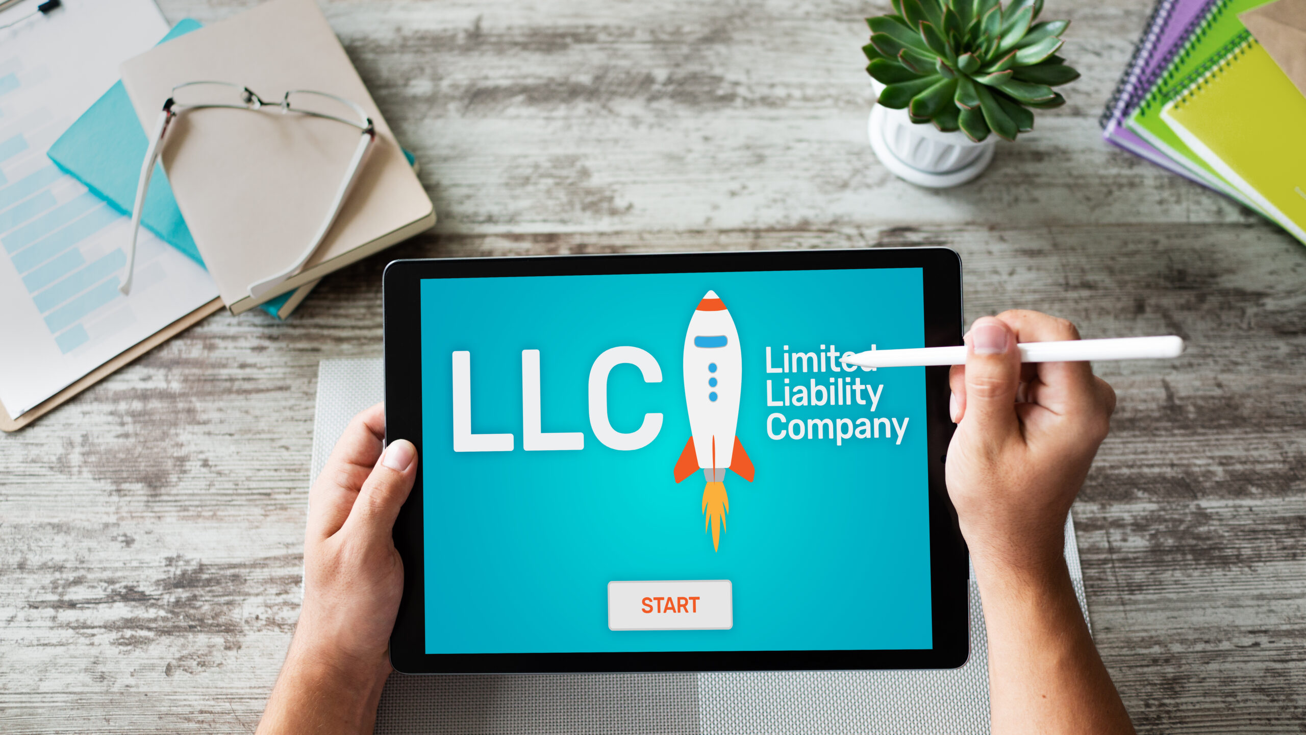 Overhead view of business professional holding a tablet that says ‘LLC - Limited Liability Company’