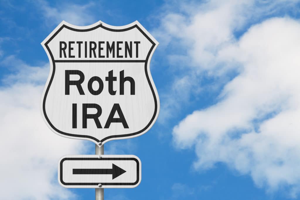 road sign with retirement and roth ira written on in blue sky