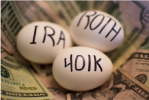 Three eggs labeled "IRA", "Roth", and "401K" in a nest of US money, similar to a retirement nest egg