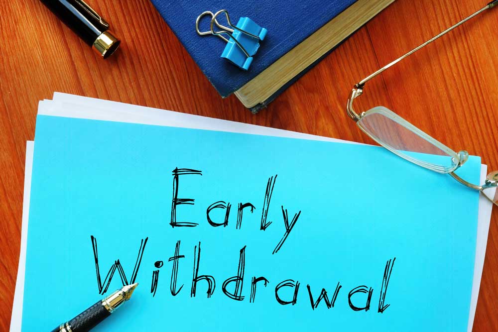 Blue paper with "early withdrawal" written in pen with glasses next to it on a desk to show the possibility of a withdrawal of funds from a Self-Directed IRA.