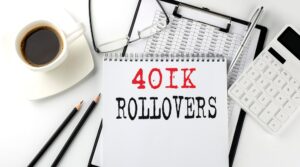 notebook that says "401K Rollovers" on a table next to a coffee cup, glasses, and spreadsheet