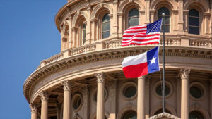 American and Texas state flags flying on the dome of the Texas State Capitol building in Austin.