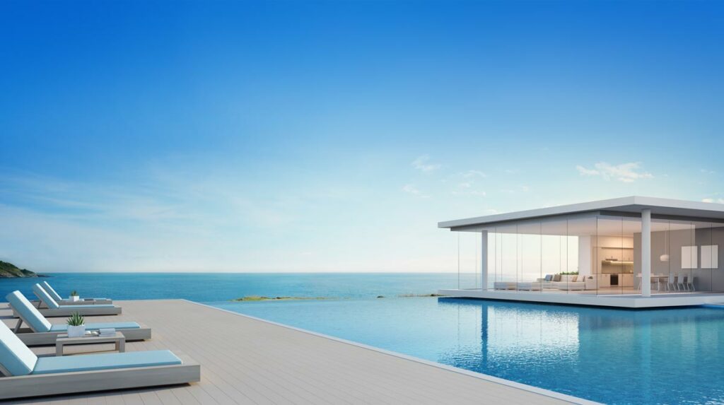 A luxurious pool, lounge chairs, and house with an ocean view.