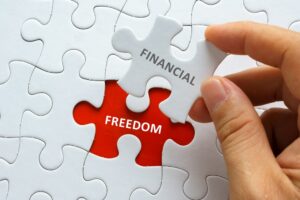 hand holding a piece of a jigsaw puzzle with words financial freedom