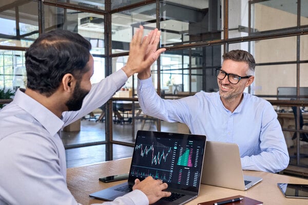 Two happy successful excited investors giving a high five celebrating successful investment in equity compensation such as stock options and stock appreciation rights in a Self-Directed IRA.