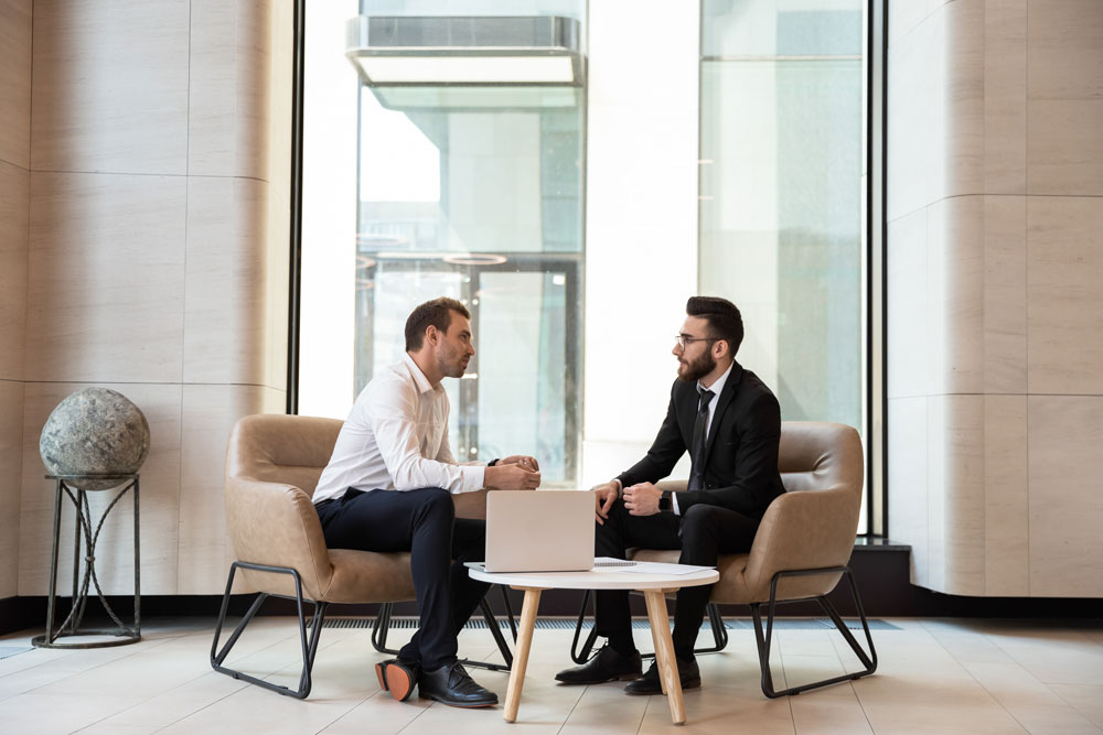 Two business men in a meeting talking about investing in a Self-Directed IRA business investment.
