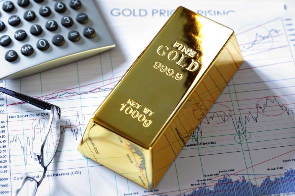 Gold bar, calculator, and glasses on an increasing trend graph to show an investment in precious metals with a Self-Directed IRA