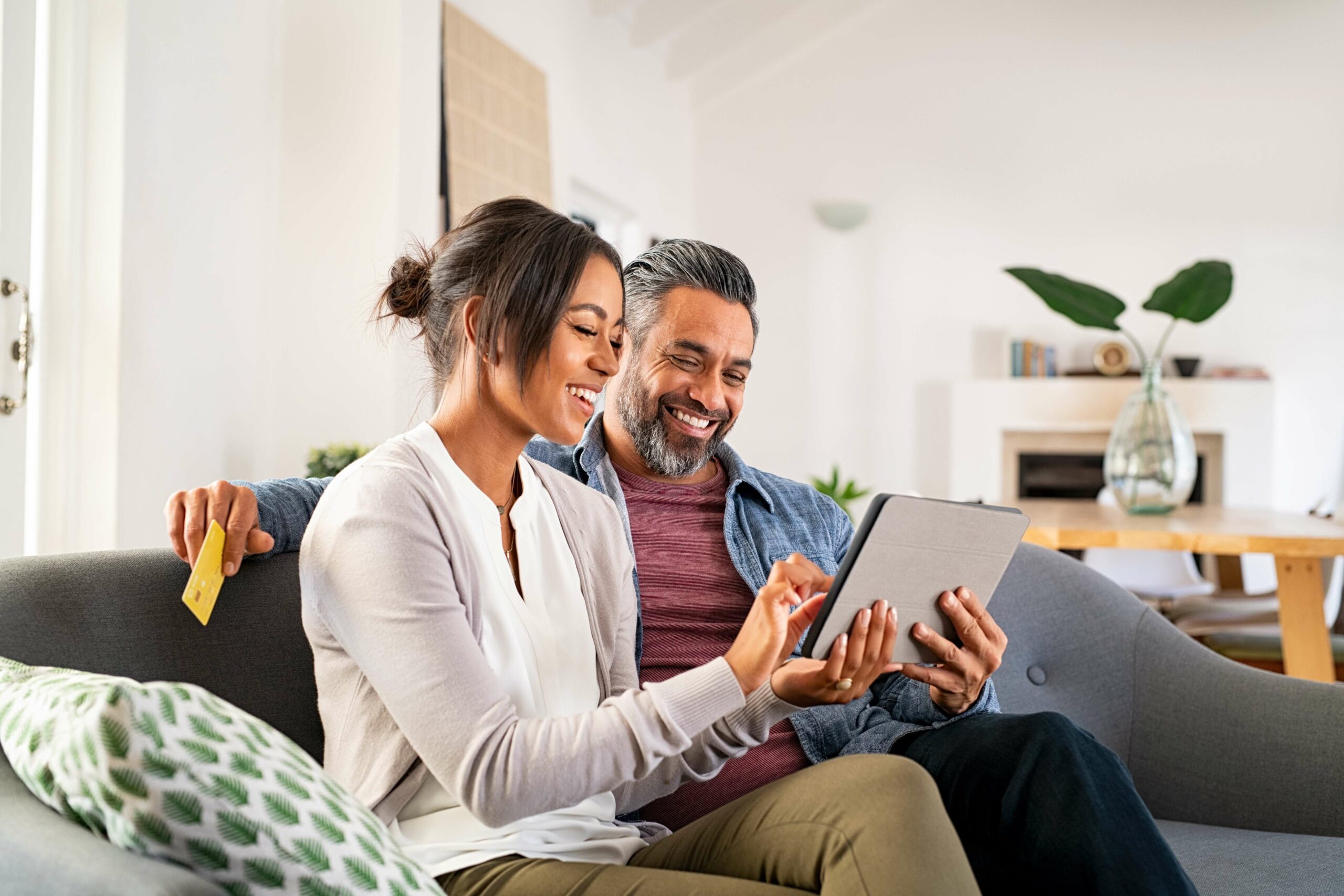 Smiling mid adult couple using digital tablet for retirement planning with a Self-Directed IRA