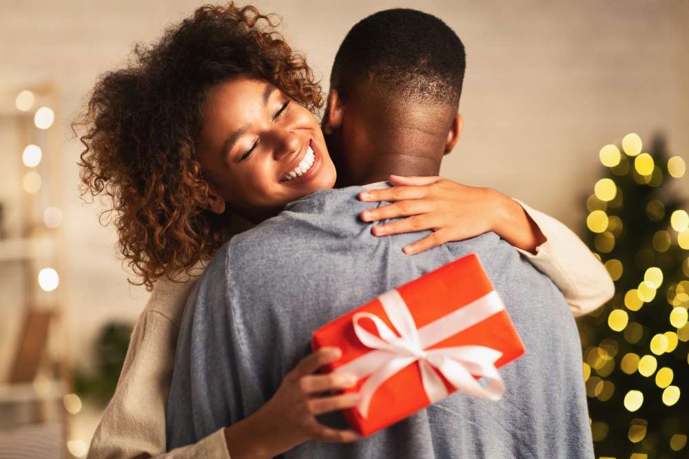A couple embraces one another amid gift giving this holiday season. 