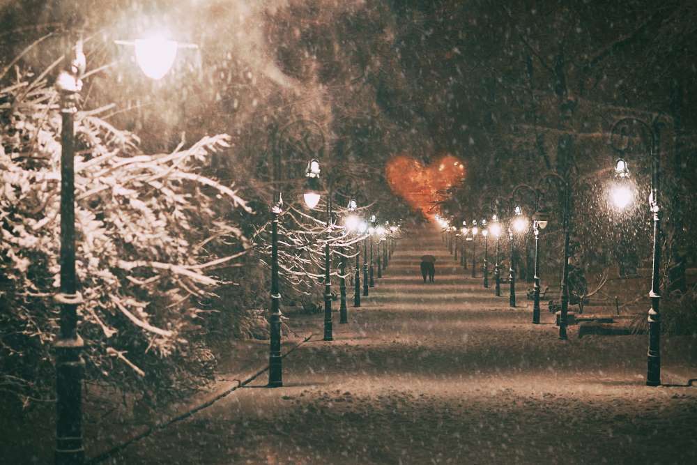 A happy, in-love couple strolls down a snow-full walkway, concluding the perfect winter date night and a promising comfortable retirement.