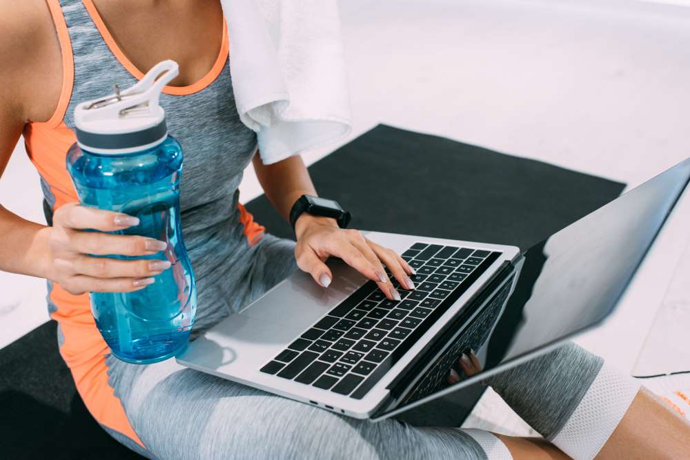 An investor completed a workout and is hydrating while writing an email to her SDIRA custodian.
