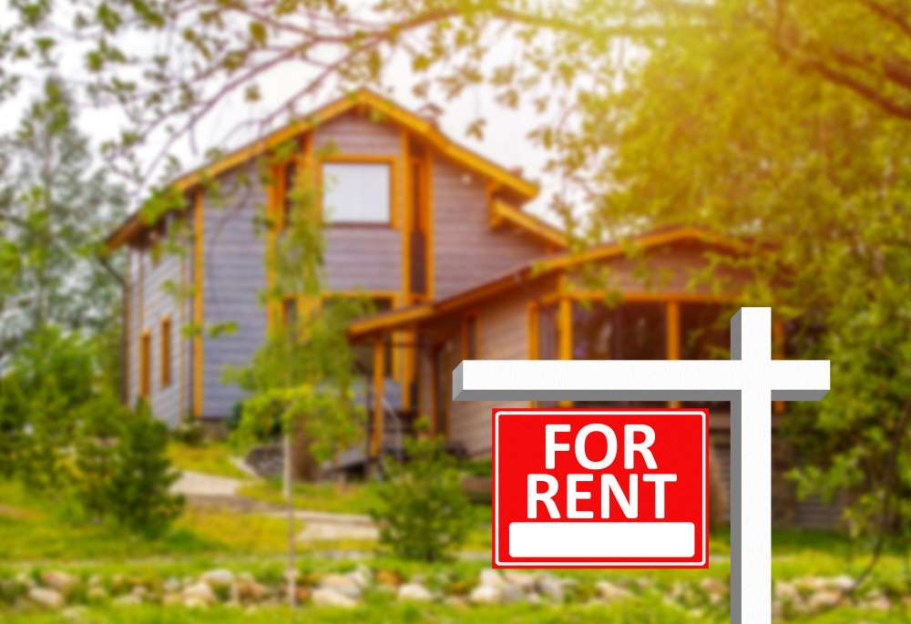 A ‘For Rent’ sign is lodged in the front of a rental property, up for rent through an investor who purchased the property through their Investment Property IRA.
