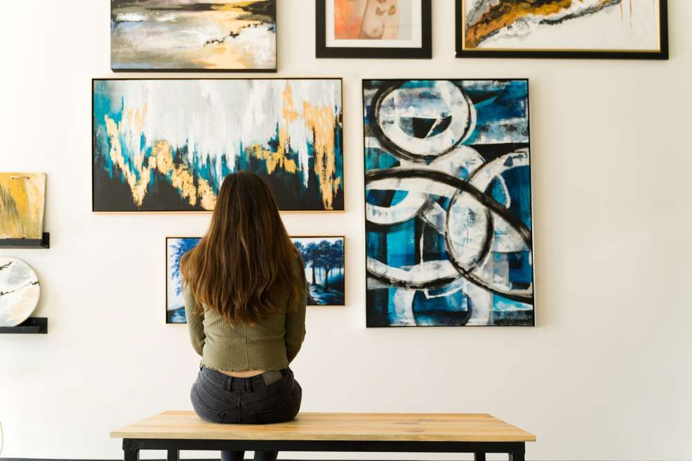An art gallery patron sits and admires a wall of paintings as she contemplates the ways in which she can use her Self-Directed IRA to help invest in the gallery. 