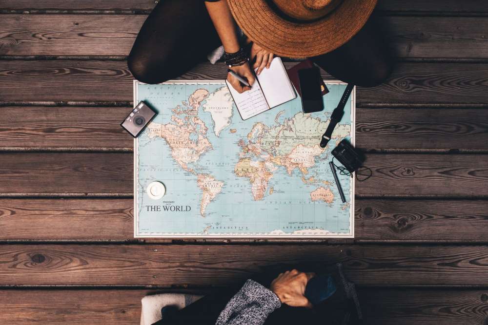 An ariel shot of a world map, as a wanderlust traveler begins planning her overseas adventures, along with her earned revenue from her Self-Directed IRA.