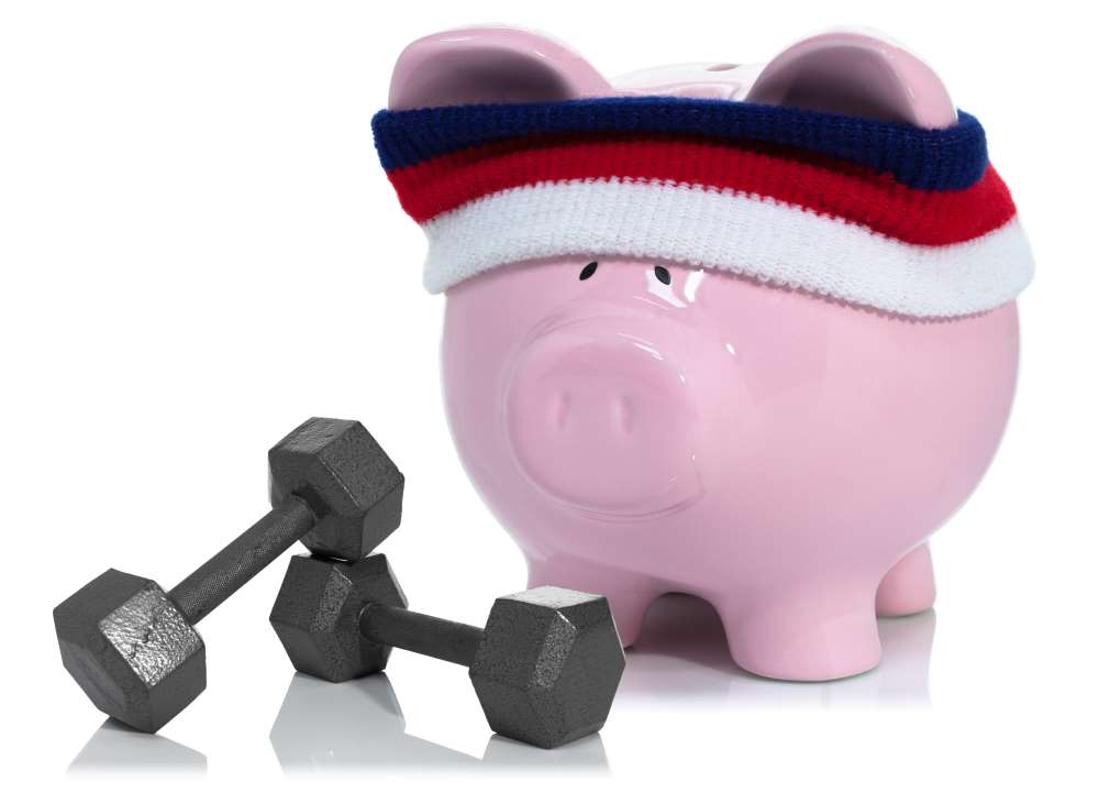 A piggy bank sports a sweatband and has weights beside him, showcasing how you can focus on saving for retirement and fitness at the same time.