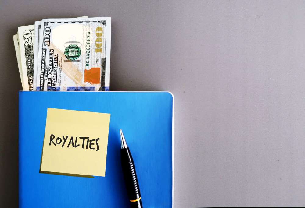 A blue folder labeled ‘Royalties’ with a wad of cash poking out, indicating that investing their Self-Directed IRA in music royalties proved to be lucrative.