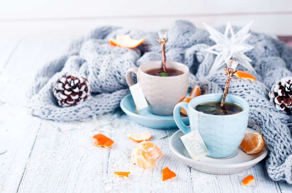 Two mugs of tea, surrounded by pinecones and blankets, which indicate that now is an ideal time to cuddle up with your significant other and plan for your retirement. 