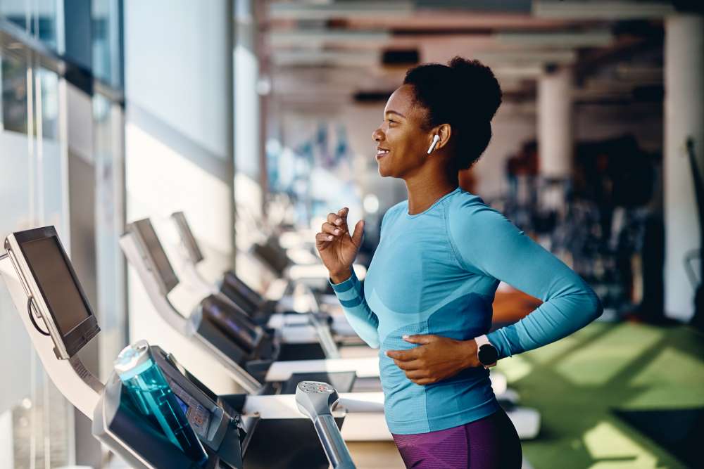 A woman runs on a treadmill, her discipline and routine aiding in achieving her new year goals. 