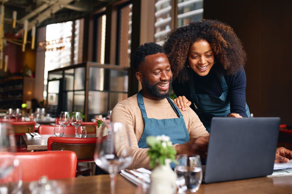Small business owners using laptop in restaurant to open a Simple IRA to plan for retirement