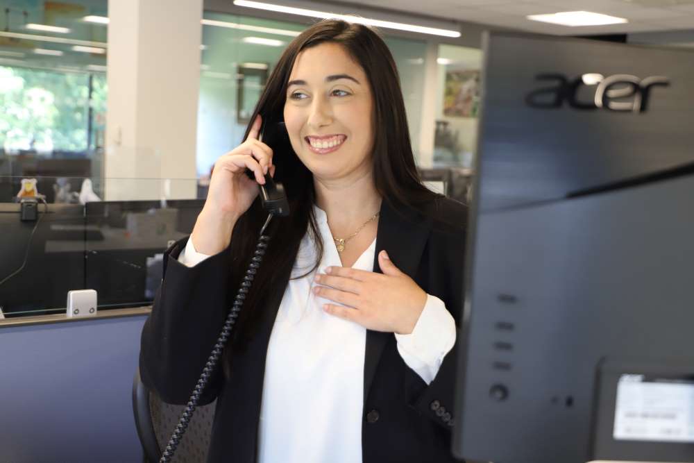 Friendly Madison Trust Self-Directed IRA Specialist smiling on the phone talking to a client.