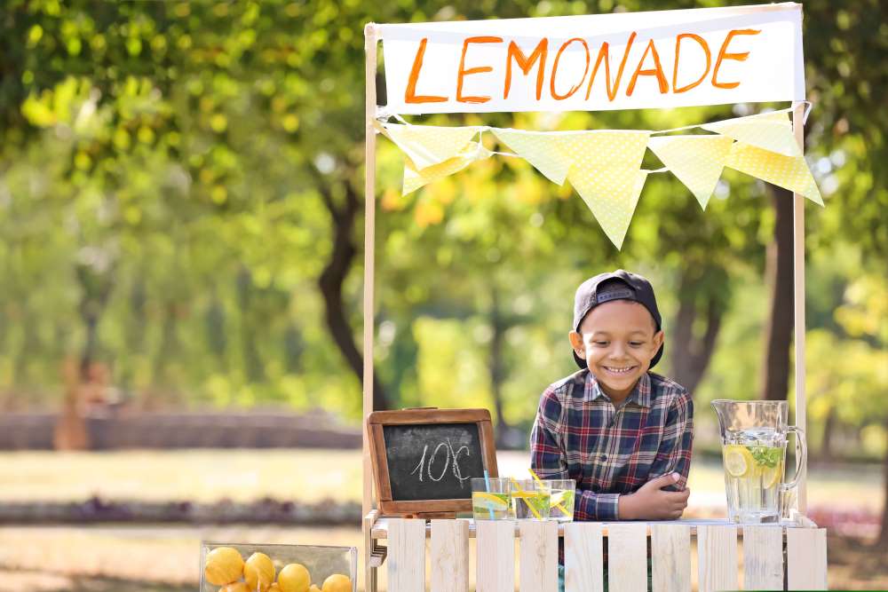 A child working at his lemonade stand in the summer, earning income so his parents can match that amount in contributions to his Custodial Self-Directed IRA.