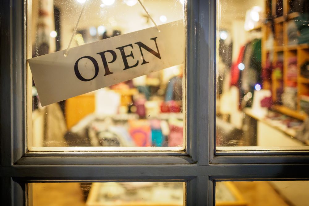 A small business has an ‘OPEN’ sign in its window, indicating that with a Self-Directed IRA, they were able to help this business raise capital.
