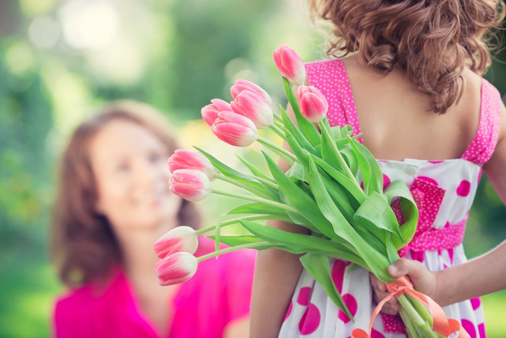 A daughter surprises her mother with flowers, displaying an act of love on this Random Acts of Kindness Day.
