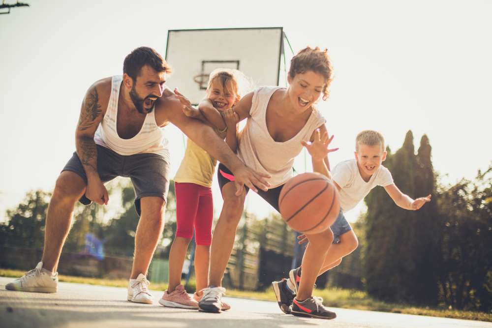 A family plays a game of basketball for fun, the parents comforted knowing their Self-Directed IRA is in good standing.