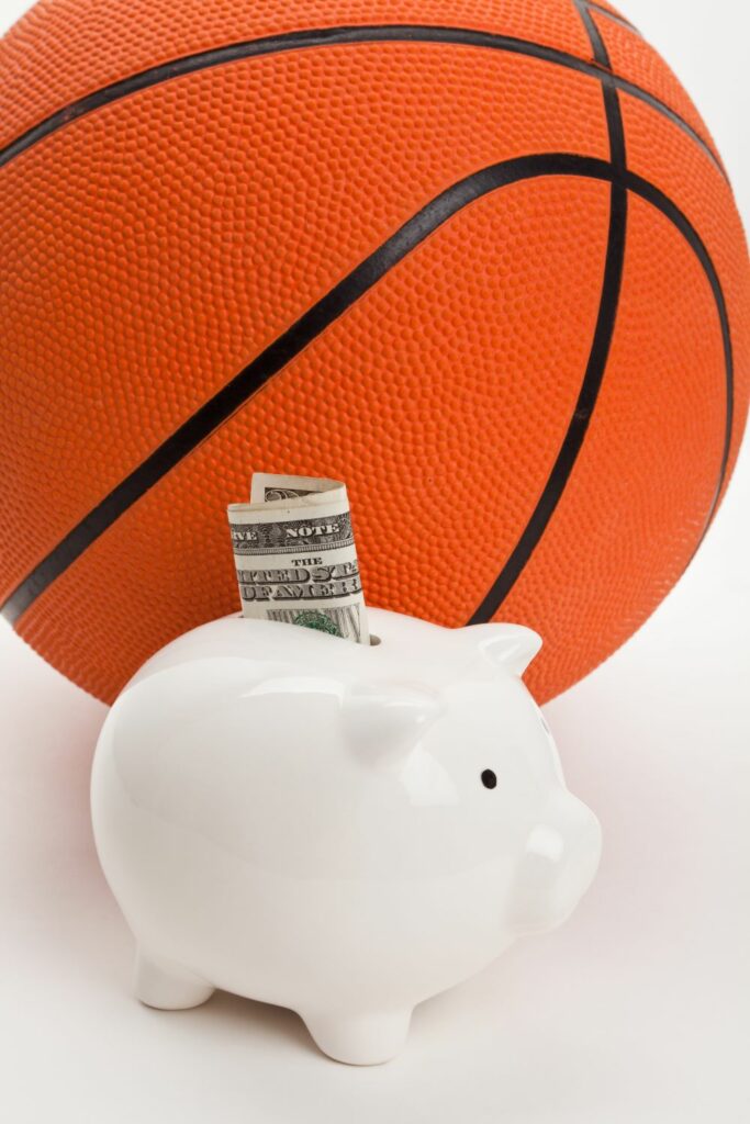 Our beloved piggy bank, stuffed to the max with cash, sitting beside a basketball, proving that with caution and awareness of prohibited transactions, you can successfully save for your retirement.
