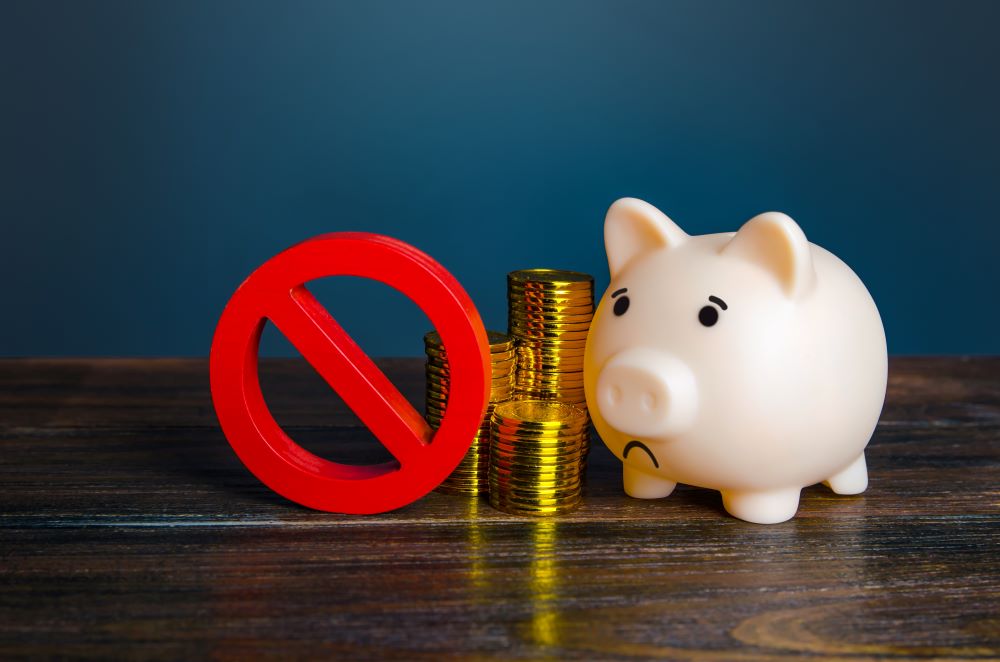 A piggy bank sits beside a prohibited symbol, as its investor was about to perform a prohibited transaction which goes against the SDIRA regulatory landscape.