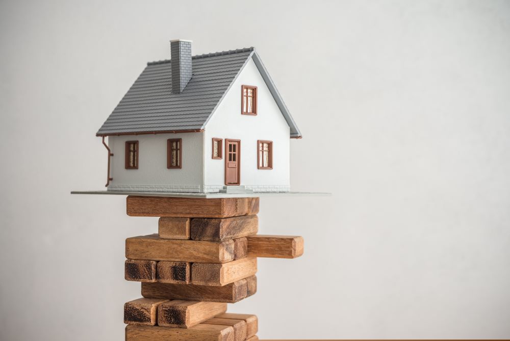 A house sits a top Jenga blocks, indicating the common mistakes made by Real Estate IRA owners.