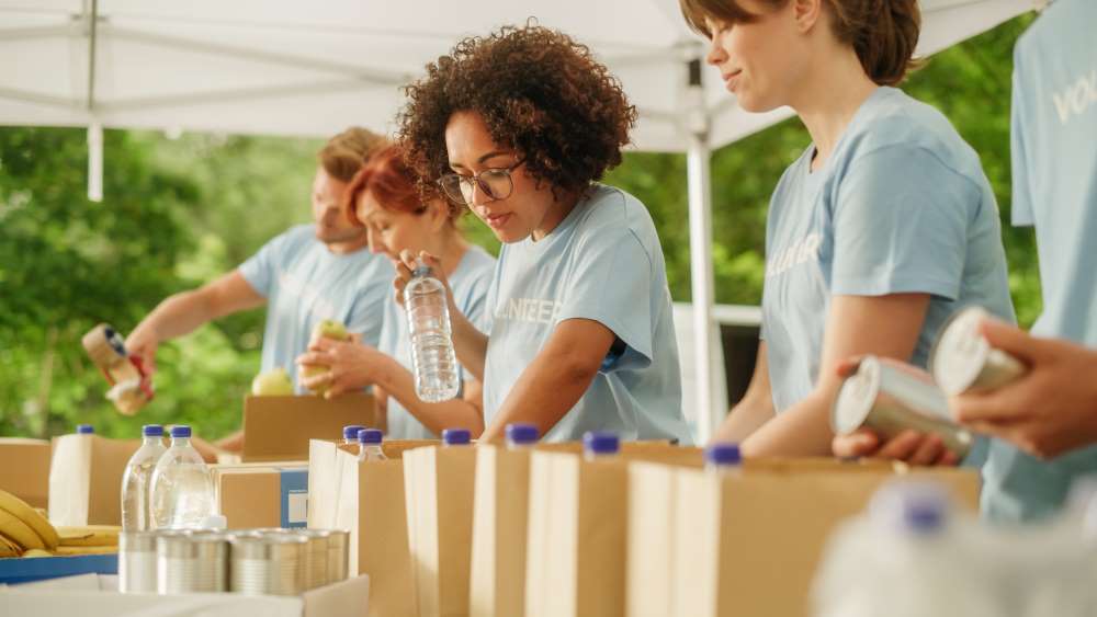 Volunteers in an assembly line packing bags of food and water to show a mission-driven small business.